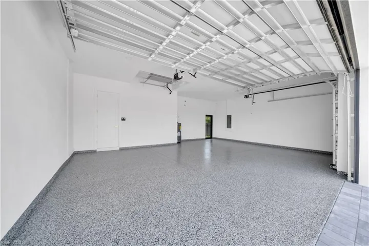 Spacious garage featuring a durable epoxy flake floor finish, white walls, and an overhead garage door mechanism