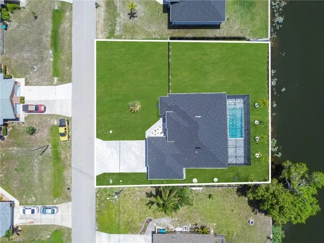 Property featuring a rectangular swimming pool with a screened enclosure, a dark shingle roof, and a paved driveway