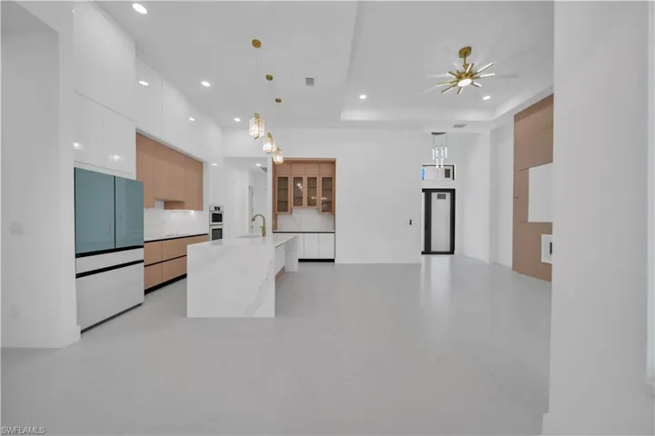 Open-concept living space with a contemporary kitchen featuring a waterfall island, integrated appliances, recessed lighting, and a modern ceiling fan