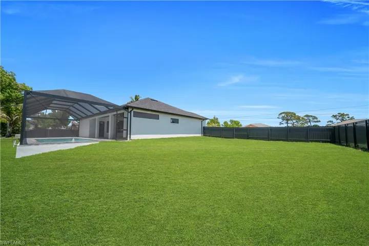 Spacious green lawn with a dark-toned privacy fence