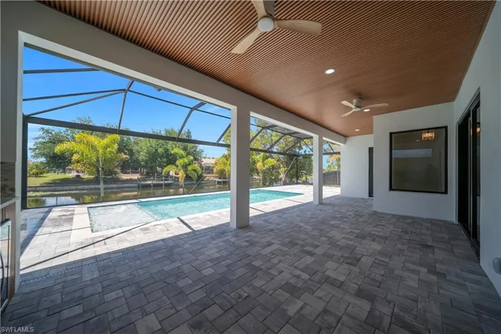 Expansive screened patio featuring paver flooring, a wood-finish slatted ceiling, recessed lighting, and ceiling fans