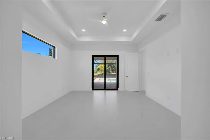 Master Bed room with white walls, light-toned flooring, and a tray ceiling featuring recessed lighting and a ceiling fan