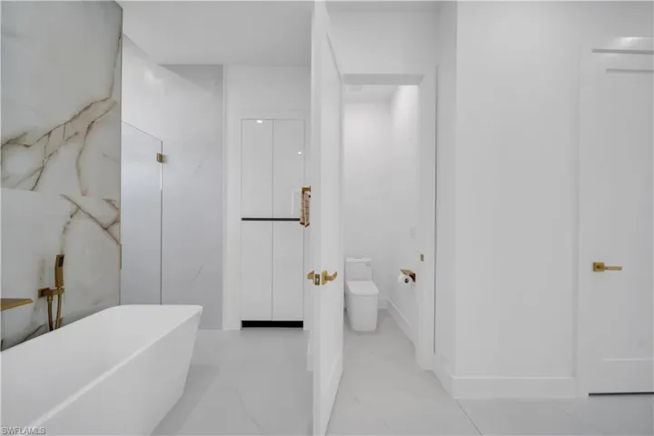 Contemporary bathroom featuring a freestanding tub, a walk-in shower with glass enclosure, large format tile flooring, and integrated storage cabinetry