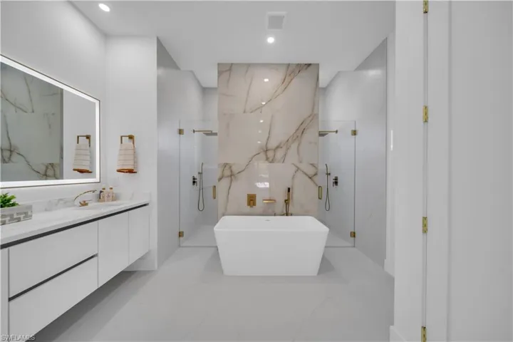 Freestanding rectangular bathtub centered within a spacious bathroom, flanked by two glass-enclosed shower areas
