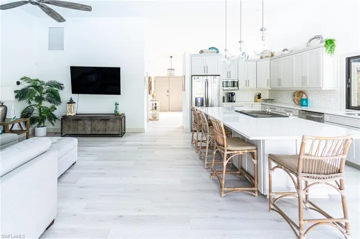 Kitchen with a center island, open floor plan, a kitchen breakfast bar, light wood-style flooring, and light stone countertops