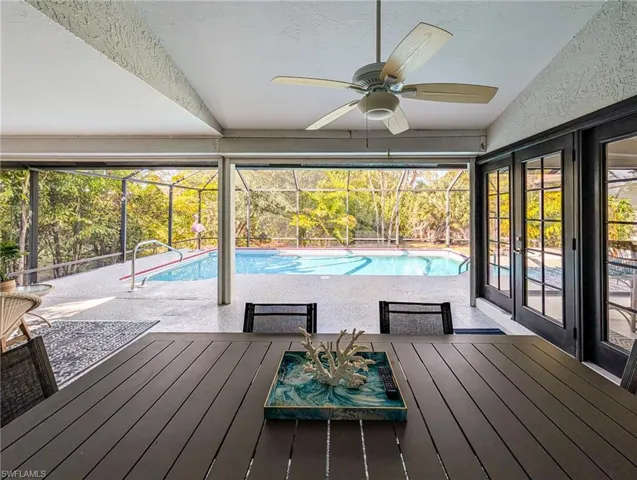 Outdoor pool featuring a sunroom, glass enclosure, a patio, and a wooden deck