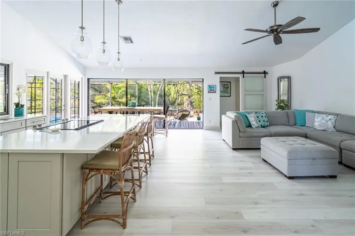 Living room featuring vaulted ceiling, a barn door, light wood finished floors, and ceiling fan