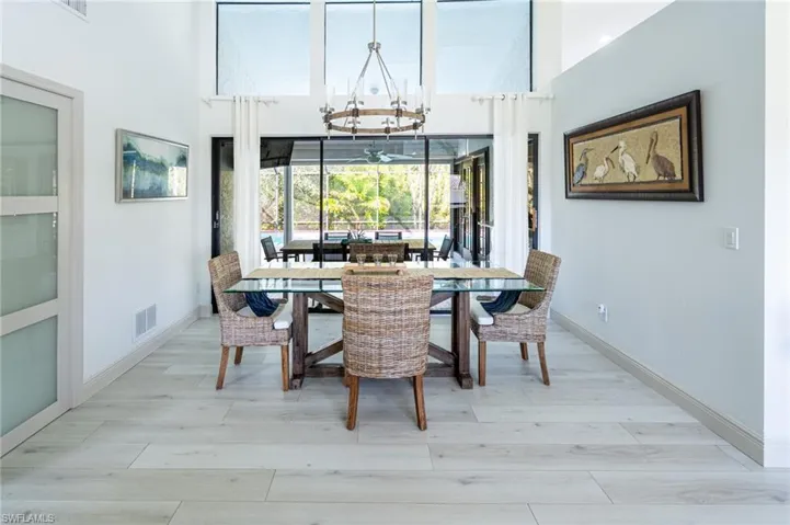 Dining space featuring light wood-style flooring, suspended lighting, and a high ceiling