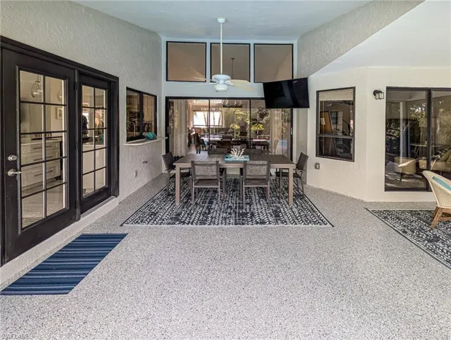 Dining space featuring a textured wall, a ceiling fan, and dark aggregate flooring