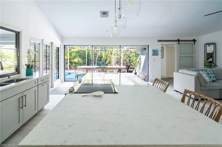 Kitchen with a barn door, a breakfast bar area, light stone countertops, open floor plan, and pendant lighting