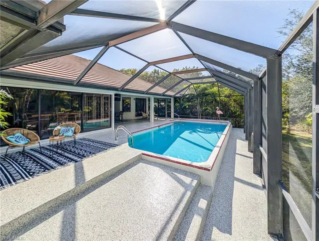 Outdoor pool with a patio, a sunroom, and glass enclosure