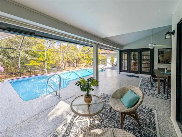Swimming pool with french doors, a sunroom, glass enclosure, and a patio area
