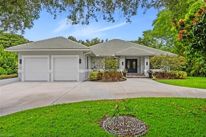Single story home with a concrete circular driveway, and attached tandem 3-car-garage