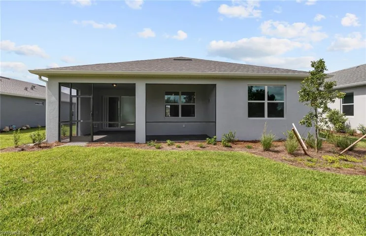 Rear view of house with a sunroom and a lawn