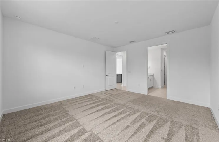 Unfurnished bedroom featuring ensuite bath and light colored carpet