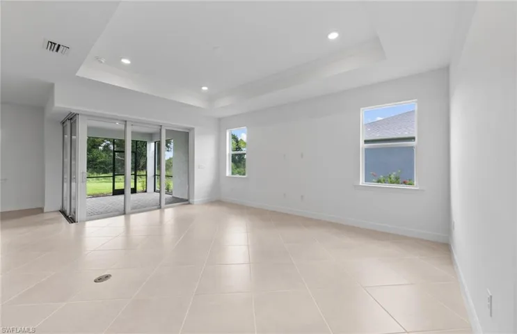 Tiled empty room with a tray ceiling and a wealth of natural light