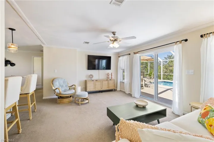 Living room featuring light carpet, baseboards, visible vents, and crown molding