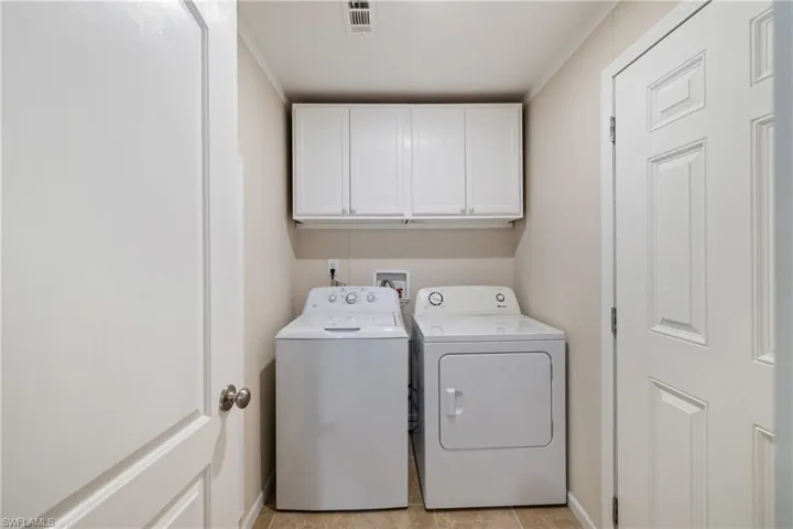 Laundry area with cabinet space, visible vents, baseboards, and separate washer and dryer