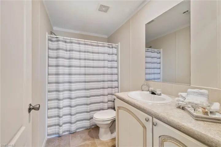 Bathroom featuring toilet, vanity, visible vents, and crown molding
