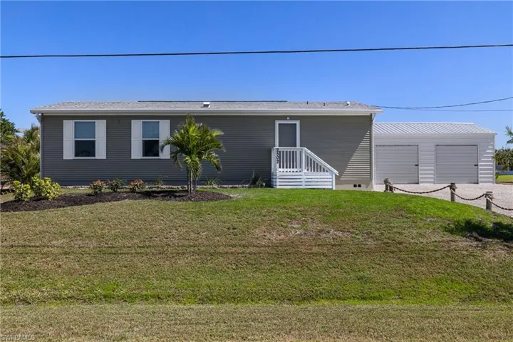 View of front of property featuring an outdoor structure and a front yard