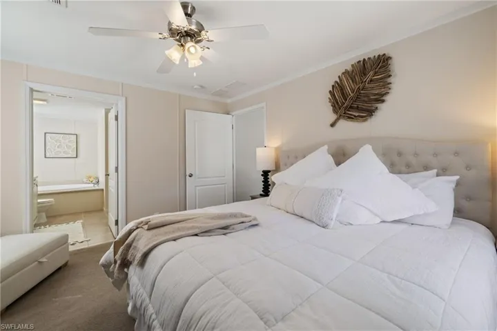 Carpeted bedroom with ceiling fan, crown molding, and ensuite bathroom