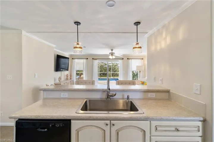Kitchen featuring black dishwasher, crown molding, light countertops, and a sink