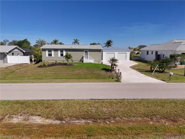 View of front of house featuring a garage, an outdoor structure, a front lawn, and fence