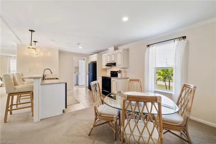 Dining space featuring light carpet, washer / clothes dryer, baseboards, and crown molding