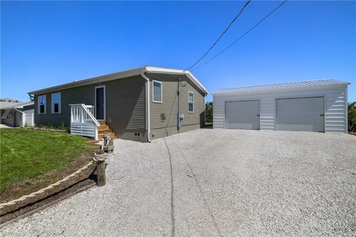 View of front of home featuring an outbuilding, crawl space, a detached garage, and a front yard