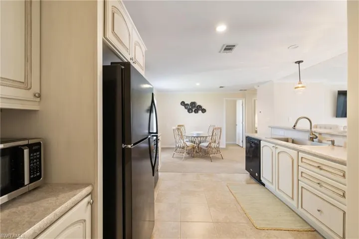 Kitchen featuring cream cabinetry, visible vents, a sink, and black appliances