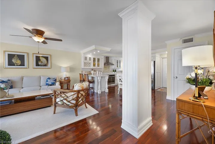 Living room with dark wood-style flooring, crown molding, and a ceiling fan