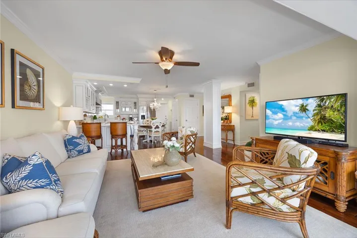 Living room featuring wood finished floors, crown molding, ceiling fan, and a chandelier