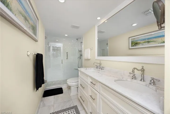 Full bathroom featuring double vanity, recessed lighting, light tile patterned floors, and a shower stall