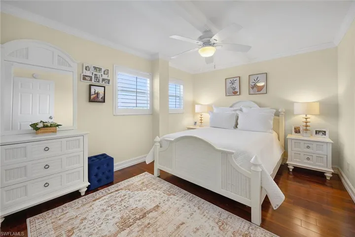 Bedroom featuring ornamental molding, dark wood-style floors, and ceiling fan