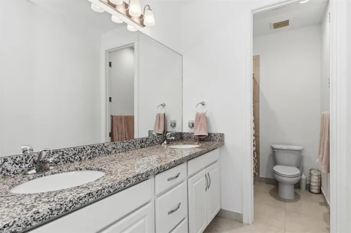 Bathroom with double vanity and light tile patterned floors