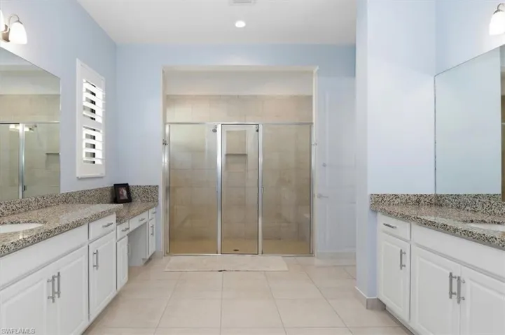 Full bath with two vanities, a shower stall, light tile patterned floors, and recessed lighting