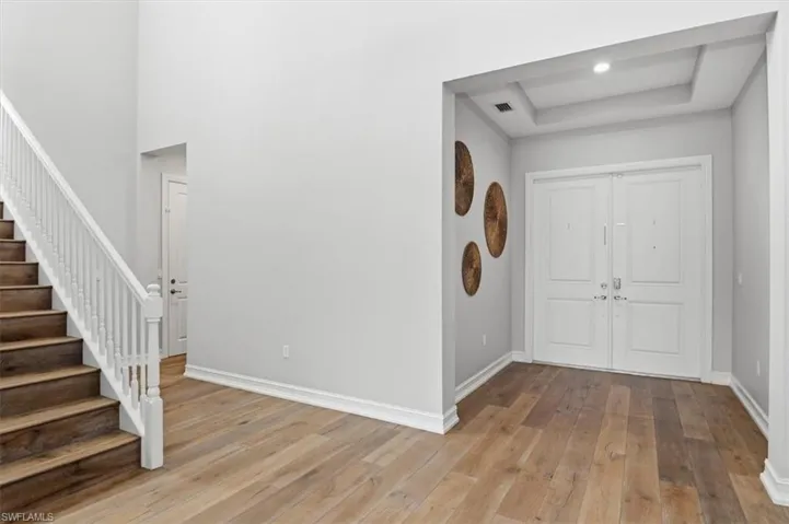 Foyer with light wood-style flooring and a tray ceiling