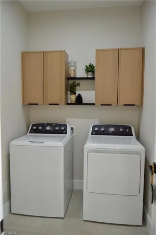 Laundry room featuring independent washer and dryer and cabinets