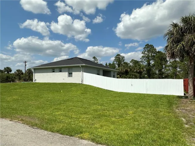 View of home's exterior featuring stucco siding, fence, and a yard
