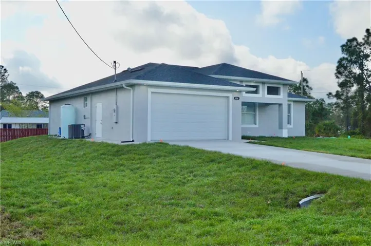 View of front of property with a front yard, a garage, and central AC unit