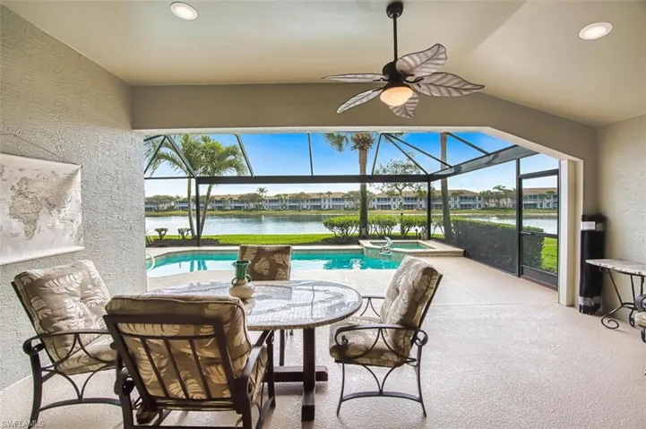 View of patio featuring a sunroom, a lanai, a pool with connected hot tub, and a water view