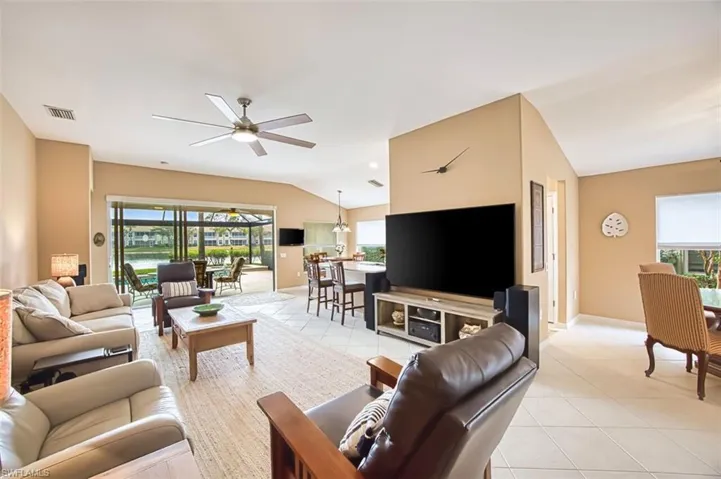 Living area with vaulted ceiling, light tile patterned flooring, ceiling fan, and a sunroom