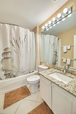 Full bathroom with shower / bath combo, vanity, and light tile patterned floors