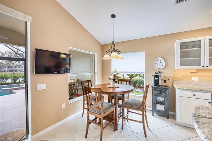 Dining area with lofted ceiling, light tile patterned floors, and suspended lighting