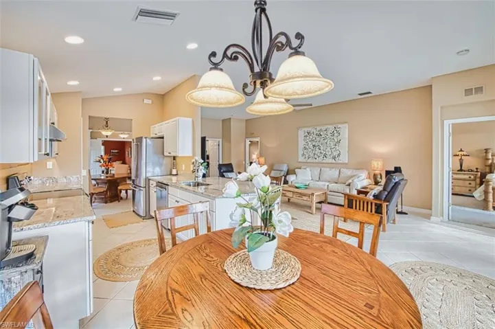 Dining space with light tile patterned floors, lofted ceiling, and hanging lights