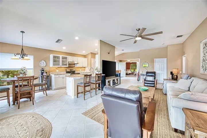 Living room featuring light tile patterned flooring, a ceiling fan, lofted ceiling, and suspended lighting