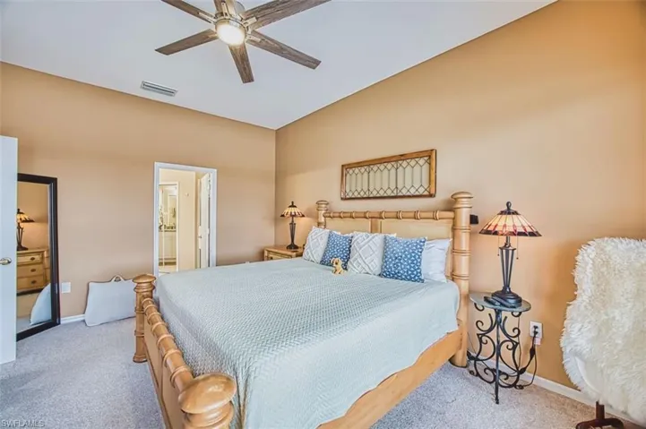 Bedroom with light carpet, ceiling fan, vaulted ceiling, and ensuite bathroom
