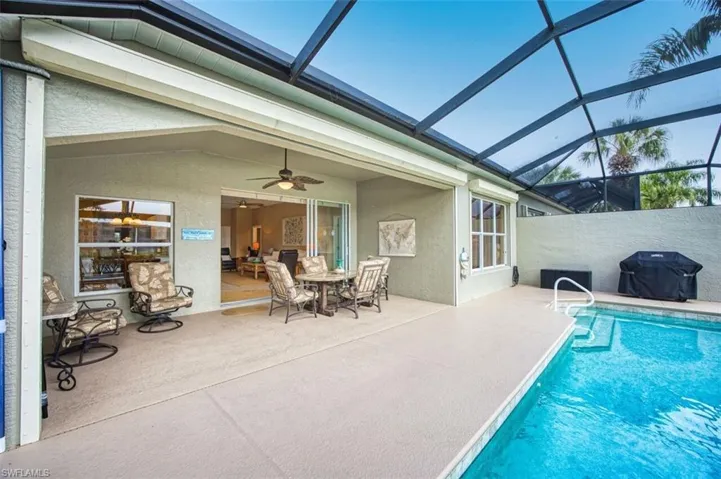 Outdoor pool with a sunroom, a grill, glass enclosure, and a patio