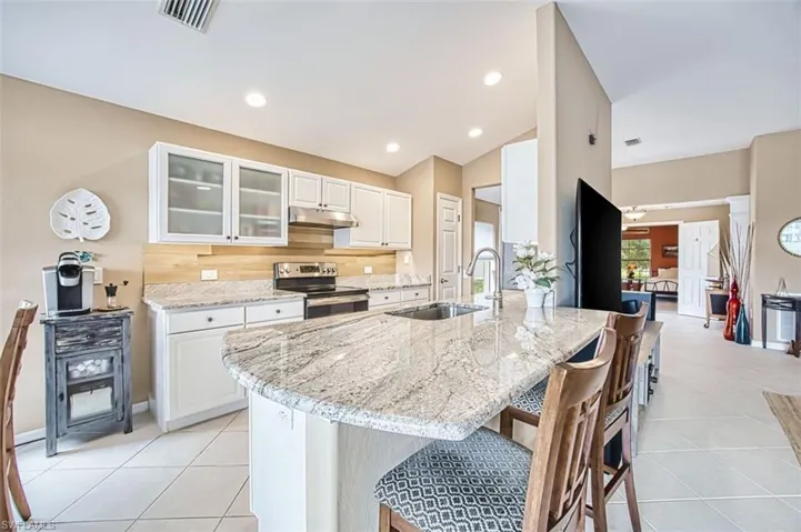 Kitchen with white cabinetry, light stone counters, stainless steel electric stove, lofted ceiling, and glass insert cabinets