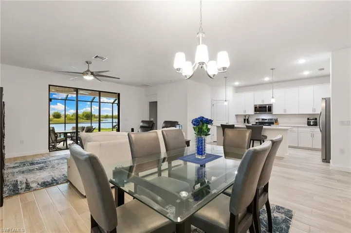 Dining area with light wood-style flooring, a ceiling fan, a chandelier, a water view, and recessed lighting